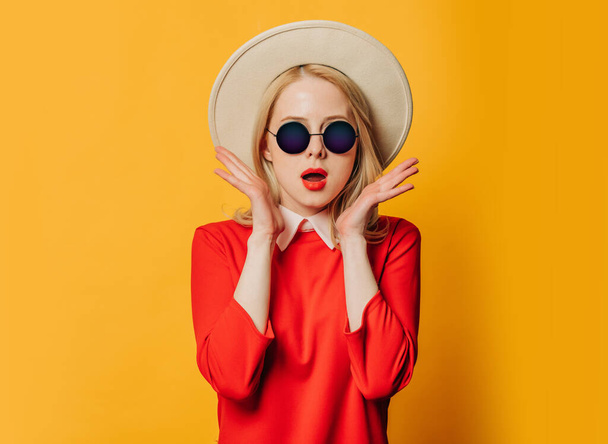 Stylish blonde hair woman in red dress and sunglasses on yellow background - Photo, Image