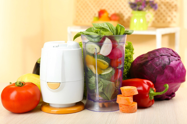 Blender with fresh vegetables on kitchen table - Foto, afbeelding