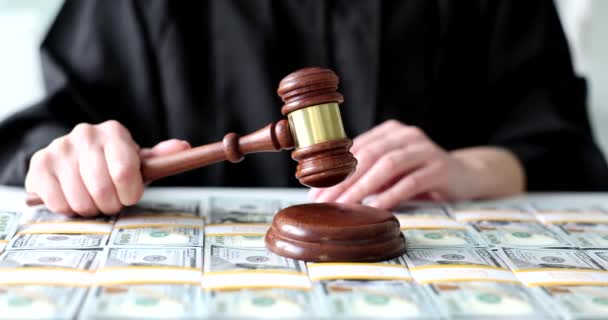 Juez de túnica negra listo para emitir veredicto en caso de robo de dinero. Mujer sostiene mazo por encima de bloque de sonido de madera en pilas de dólares - Metraje, vídeo