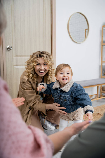 happy woman in trench coat and carefree girl in denim jacket visiting parents at home - Foto, Imagem
