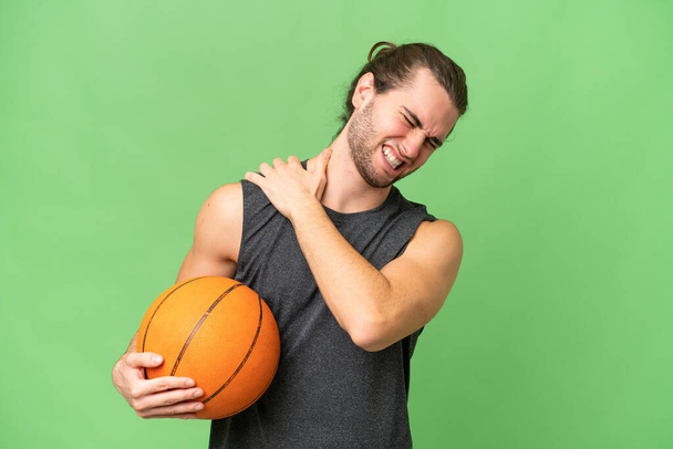 Giovane giocatore di basket uomo su sfondo isolato che soffre di dolore alla spalla per aver fatto uno sforzo - Foto, immagini