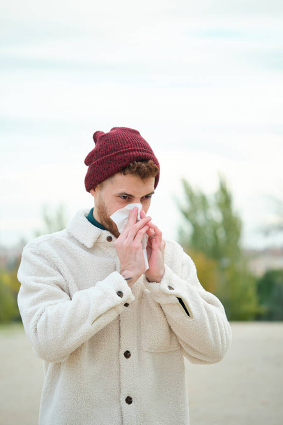 冬にはラテン系の青年が鼻を組織に吹き込む。寒い天気。フル. - 写真・画像