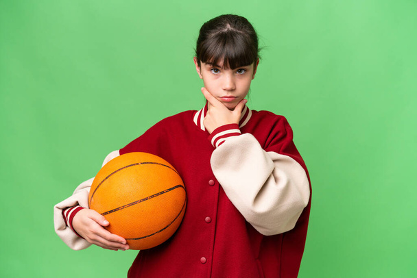 Mały kaukaski dziewczyna gra w koszykówkę na odosobnionym tle myślenia - Zdjęcie, obraz