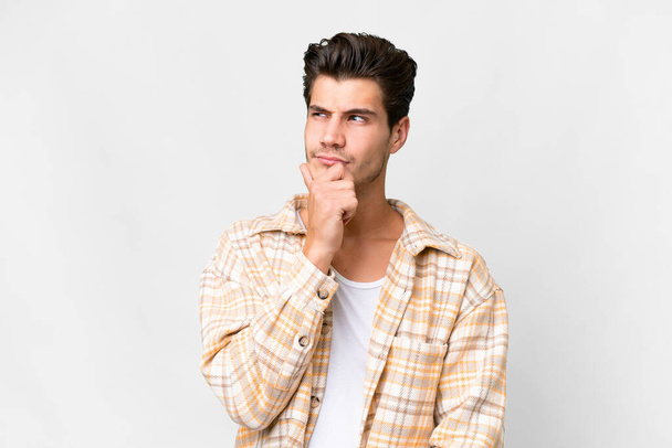 Young handsome caucasian man over isolated white background having doubts and with confuse face expression - Valokuva, kuva