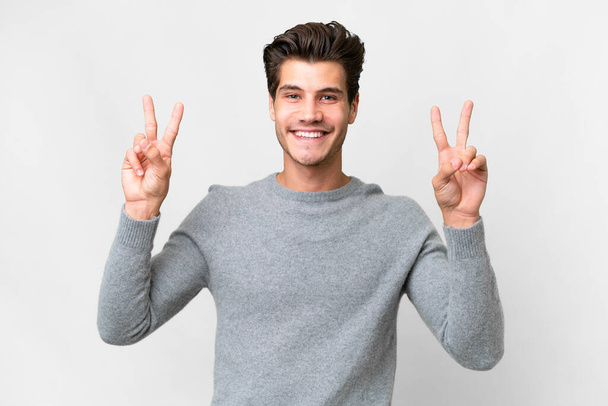 Junger gutaussehender kaukasischer Mann auf isoliertem weißem Hintergrund, der mit beiden Händen ein Siegeszeichen zeigt - Foto, Bild