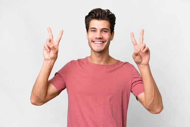 Junger gutaussehender kaukasischer Mann auf isoliertem weißem Hintergrund, der mit beiden Händen ein Siegeszeichen zeigt - Foto, Bild