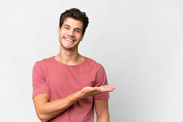 Fiatal jóképű kaukázusi férfi izolált fehér háttér bemutatja egy ötlet, miközben nézett mosolyogva felé - Fotó, kép