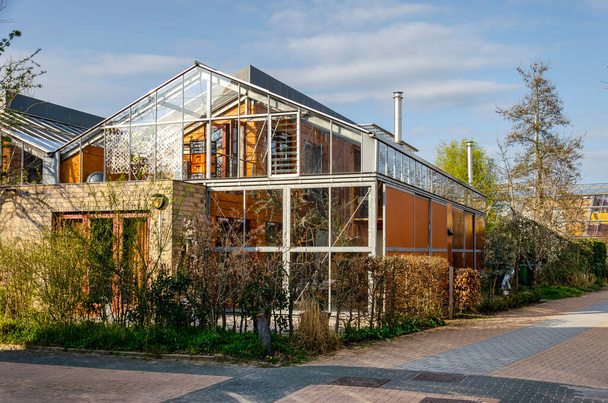 Culemborg, Países Bajos, 8 de abril de 2023: calle en el barrio de Lanxmeer con casas ecológicas con fachadas construidas principalmente con madera y vidrio - Foto, imagen