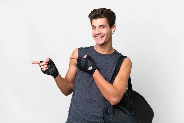 Young sport caucasian man with sport bag over isolated white background pointing finger to the side and presenting a product - Foto, Imagem