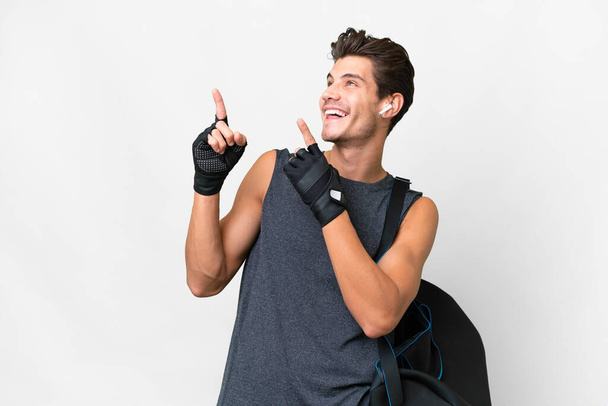 Joven hombre caucásico deporte con bolsa de deporte sobre fondo blanco aislado apuntando con el dedo índice una gran idea - Foto, Imagen