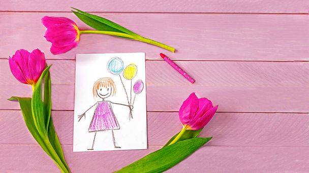 Children s drawing of Mother s Day greetings, purple tulip flowers and pencil on pink wooden background. Mother s Day concept - Фото, изображение
