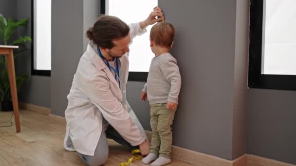 Padre e hijo médico midiendo niño en la clínica - Metraje, vídeo