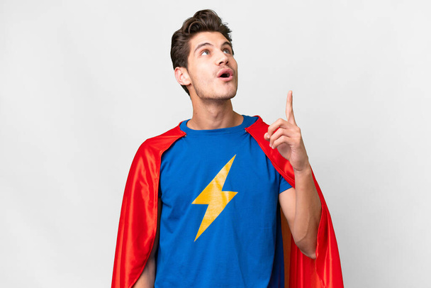Super Hero caucasian man over isolated white background pointing up and surprised - Photo, Image