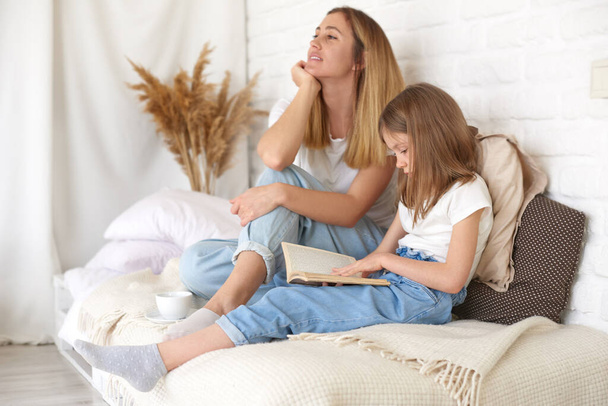 Studium zu Hause. Tochter und Mutter lesen Buch auf dem Bett zu Hause. Zeit miteinander verbringen - Foto, Bild