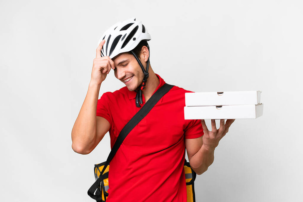 Pizza delivery man with work uniform picking up pizza boxes over isolated white background laughing - Photo, image