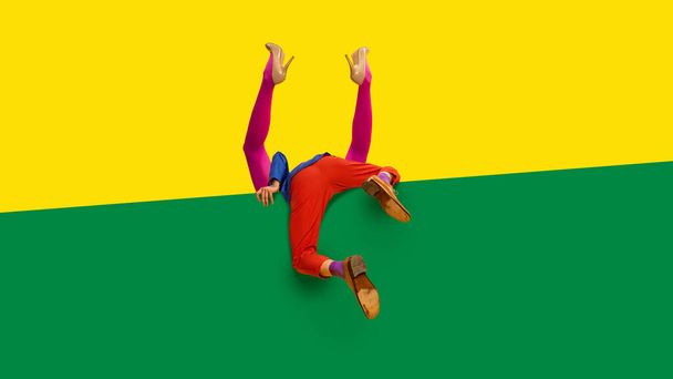 Male and female legs in pink tights and red trousers hiding, sticking out vivid yellow and green background. Love, romance and relationship. Complementary colors. Concept of fashion, creative vision - Fotografie, Obrázek