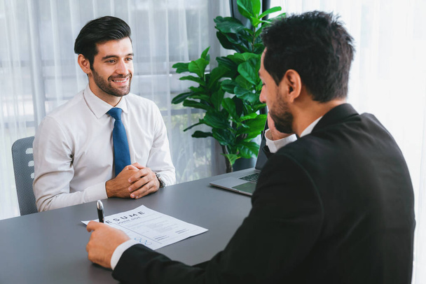 Interviewing job applicant in office with resume paper. Candidate wear suit for formal conversation with interviewer. Recruitment process with question about career and work experience. Fervent - 写真・画像