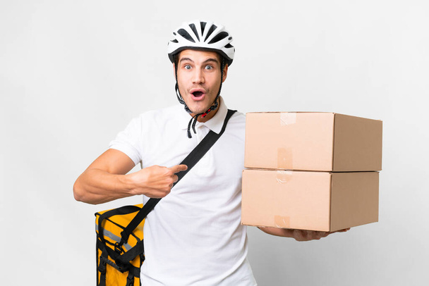 Livraison homme portant un casque vélo sur fond blanc isolé avec expression faciale surprise - Photo, image