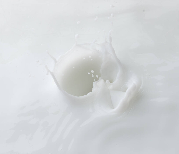 Cosmetic container white lotion droplet fly splashing. Milk lotion pour float to cosmetic bottle. Moisturizer lotion explosion spill. White background isolated high speed shutter freeze top view - Photo, Image