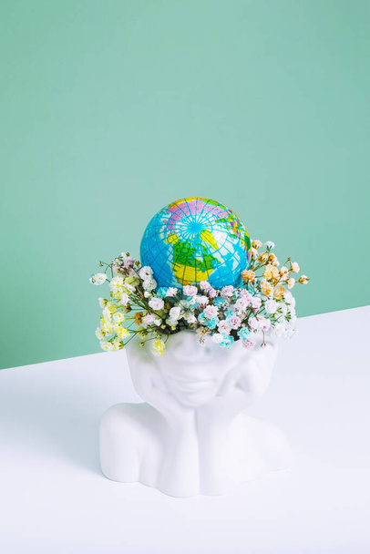 Save the planet, Earth day concept. Creative plaster vase head-shape with flowers and world globe. - Foto, Imagen