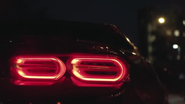 Luce posteriore nera per auto sportive che brilla nel buio di una città notturna, lampeggiante luce di parcheggio - Filmati, video