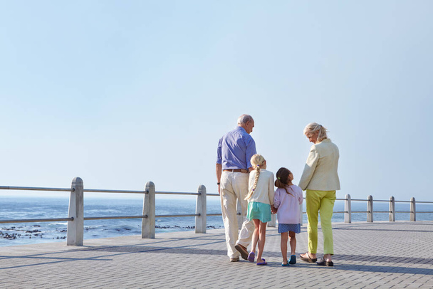 Hoy somos solo nosotros y los nietos. abuelos caminando de la mano con sus nietas en un paseo marítimo - Foto, imagen