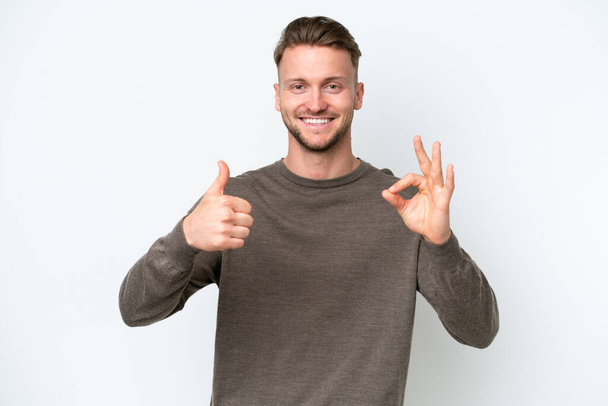 Young blonde caucasian man isolated on white background showing ok sign and thumb up gesture - Photo, Image