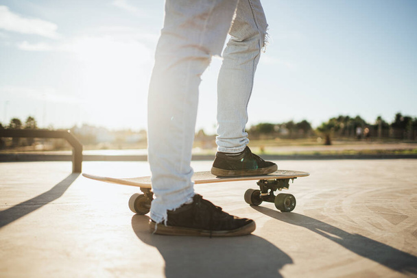Terug verlicht shot van skater 's voeten op skateboard. Hij staat op het punt te gaan rijden. - Foto, afbeelding