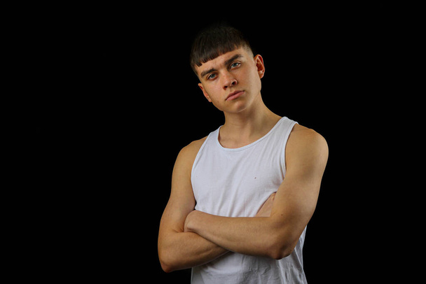 Portrait of a teenage boy in a white sleeveless top against a black background - Photo, image