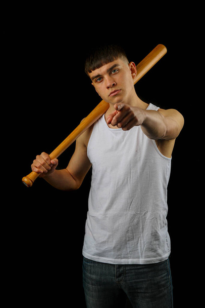 Teenage boy in a white sleeveless top holding a baseball bat in a threatening way - Fotoğraf, Görsel