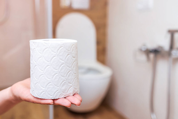 close-up, as mulheres mão rasga fora da folha de rolo de papel higiênico no fundo do banheiro. O conceito de problemas de saúde, tratamento de hemorróidas, intestinos. Higiene pessoal e saúde - Foto, Imagem
