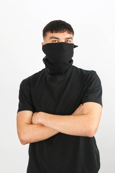 Teenage boy wearing a black mask against a white background - Foto, imagen