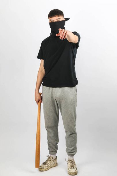 A teenage boy with a basball bat wearing a mask against a white background - Photo, Image