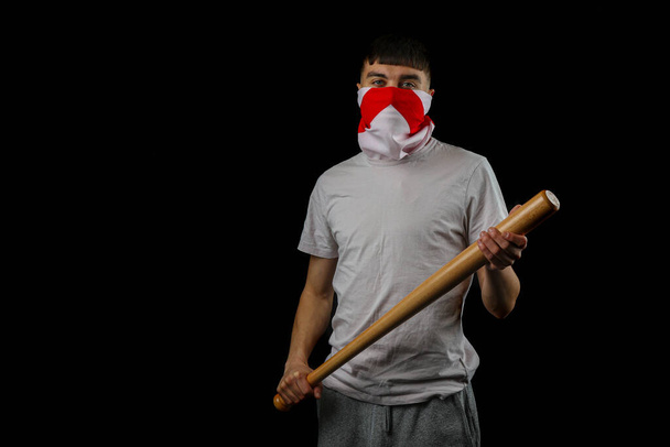 A teenage boy wearing an England flag carrying a baseball bat against a black background - Foto, Bild