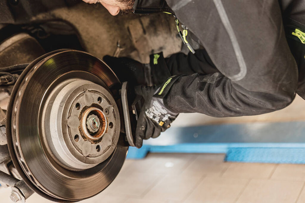 Skilled mechanic expertly replaces brake pads on a car with precision and care. - Foto, imagen