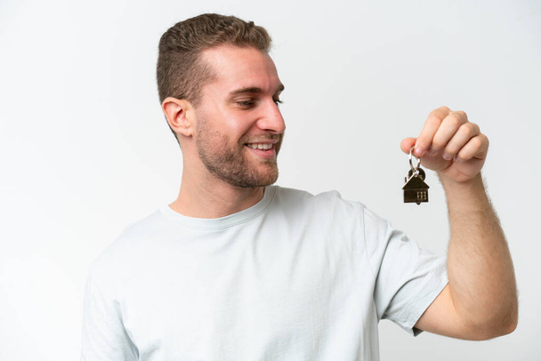 Young caucasian man holding home keys isolated on white background with happy expression - Фото, изображение