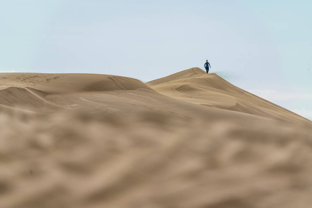 Турист среди песчаных дюн в пустыне. Удивительный день с голубым небом. Аргентина, Южная Америка. Высокое качество фото - Фото, изображение