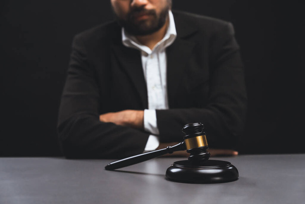 Konzentrierte hölzerne Hammer mit grundiertem Hintergrund des Rechtsanwalts im schwarzen Anzug sitzen auf seinem Bürotisch, Symbol für rechtliche Gerechtigkeit und Integrität, ausgewogene und ethische Entscheidung vor Gericht Gleichgewicht - Foto, Bild