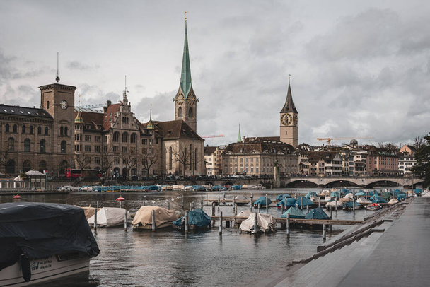 Fraumunster church in Zurich city Switzerland. Riverside view, boats parked on the river, Bridge in the distance, daytime, no recognizable people. - Fotoğraf, Görsel