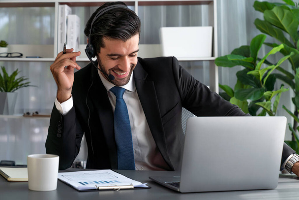 Mies Call Center operaattori tai telesales edustaja istuu hänen toimisto työpöytä yllään kuulokkeet ja keskustelun asiakkaan kanssa, joka tarjoaa asiakaspalvelua tukea tai tehdä vakuuttava myynti. kiihkeä - Valokuva, kuva