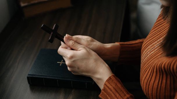 Hands together in prayer to God along with the bible In the Christian concept and religion, woman pray and Bible on the wooden table - Фото, изображение