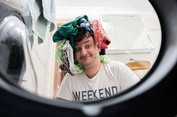 Funny man view from washing machine inside. Male does laundry daily routine.   - Φωτογραφία, εικόνα