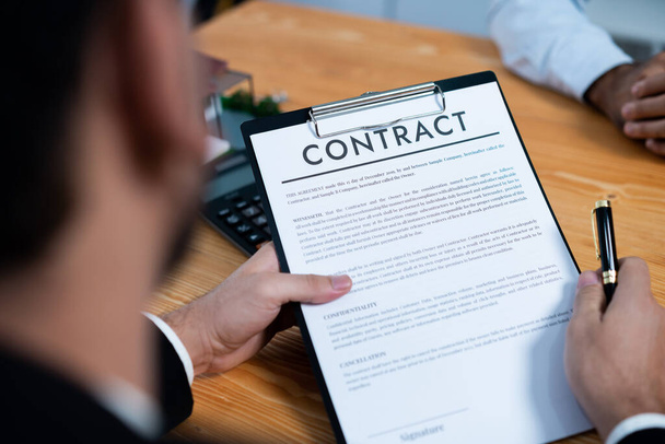 Focus house loan contract agreement with blurred client review legal document with real estate agent while discuss term and property ownership. Client reading agreement for making decision. Fervent - Photo, Image