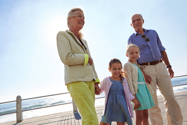 Fueron bendecidos con dulces nietos. abuelos caminando de la mano con sus nietas en un paseo marítimo - Foto, imagen