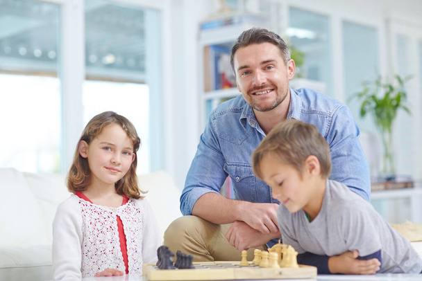 Oma pikku shakkikerhomme. Isä pelaa shakkia poikansa ja tyttärensä kanssa kotona. - Valokuva, kuva