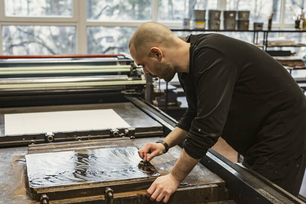 O artista está limpando um calcário litográfico com um coágulo e produtos químicos em uma oficina de arte. - Foto, Imagem