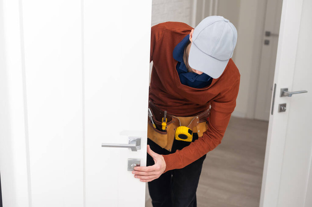 Young handyman installing a white door. - Foto, Imagen