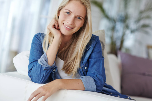Living life with a smile. Portrait of an attractive young woman relaxing on her sofa at home - Photo, Image