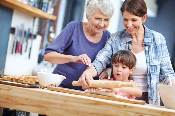 Happiness is homemade. a three generational family baking together - Фото, изображение