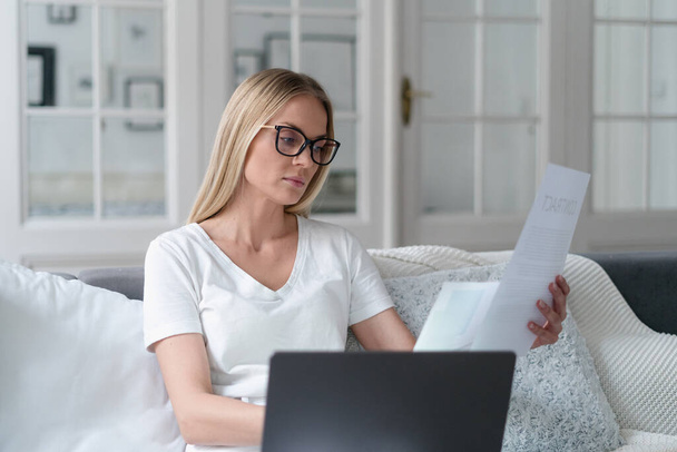 figyelmes nő visel szemüveg olvasási dokumentumot, koncentrált lány távoli munkavállaló részt vesz tanulmányozza feltételek hitelszerződés otthon - Fotó, kép